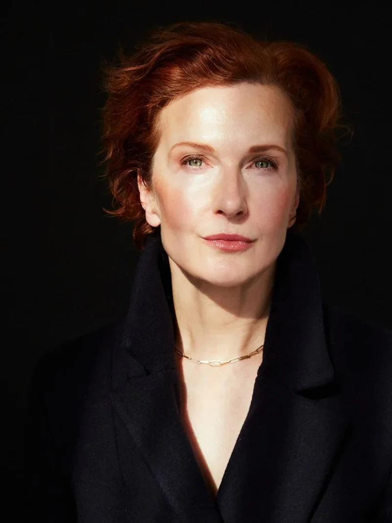 Woman in a dark blazer against a black background.